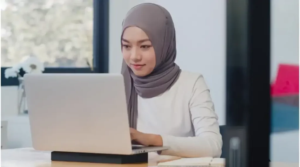 a woman wearing a head scarf and using a laptop